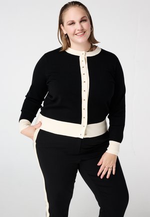 Zwarte cardigan met een crèmekleurige geribde kraag, manchetten en tailleband, voorzien van gouden knopen aan de voorkant en een zachte textuur.