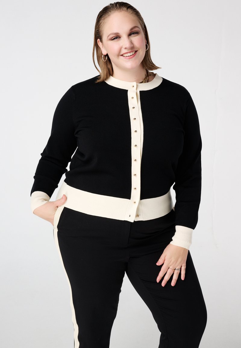 Zwarte cardigan met een crèmekleurige geribde kraag, manchetten en tailleband, voorzien van gouden knopen aan de voorkant en een zachte textuur.