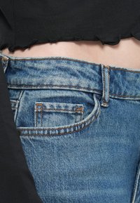Denim jeans i lyseblå med en klassisk fem-lommers design, synlige sømdetaljer og en slitt kant ved livet.