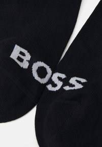 Μαύρες κάλτσες από μαλακό ύφασμα με ριμπ σχέδιο, διαθέτοντας το λογότυπο "BOSS" σε αντίθεση γκρι στα πλάγια.