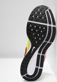 Černá gumová podrážka boty s hexagonálními vzory, zakřivený tvar, bílé a růžové akcenty. Logo Nike viditelné na boku.