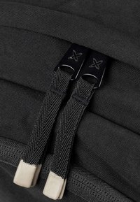 Crna tkanina torba s glatkom teksturom, dvostrukim patent zatvaračem s metalnim povlačenjem i gumiranim krajevima za lako držanje.