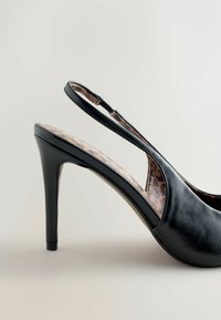 Zwarte slingback hoge hak schoen met een getextureerde afwerking en een binnenzool met luipaardprint, voorzien van een taps toelopende hak en open teen ontwerp.