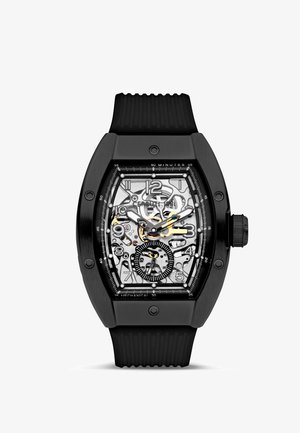 Reloj de pulsera mecánico rectangular negro con engranajes visibles, números blancos y un pequeño subesfera de segundos a las 6 en punto, equipado con una correa negra.