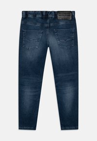 Σκούρο μπλε τζην παντελόνι με ομαλή υφή, που διαθέτει φαρδύ ζωνάκι, δύο πίσω τσέπες και μια επώνυμη δερμάτινη ετικέτα στο πίσω μέρος.