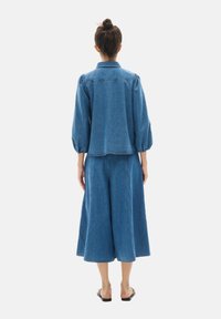 Conjunto de denim que incluye una chaqueta azul corta con mangas abullonadas y culottes anchos a juego, ambos en un lavado medio y ajuste informal.