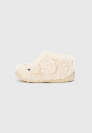 Chausson flou de couleur crème avec un bout arrondi et une surface texturée. Présente une semelle en caoutchouc avec des accents rayés colorés.