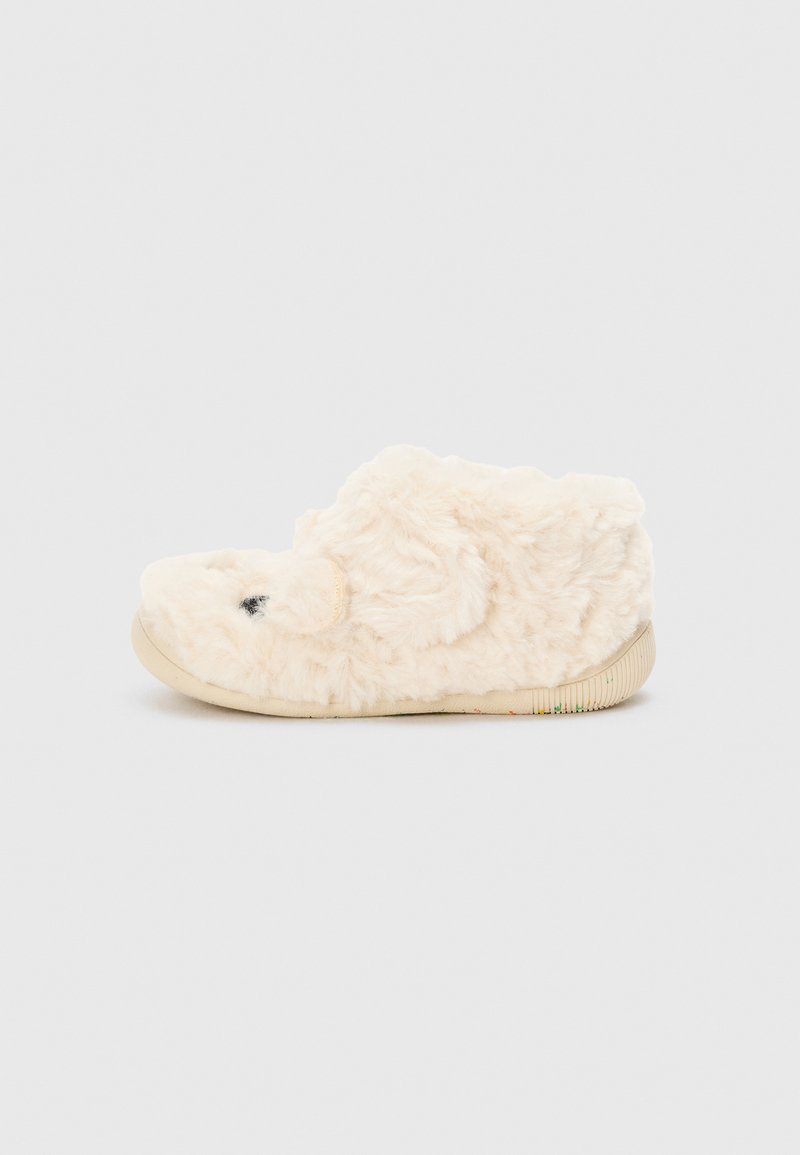 Pantofole fuzzy di colore crema, con punta arrotondata e superficie texture. Presentano una suola in gomma con accenti a strisce colorate.