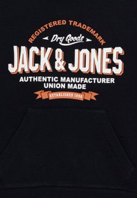 Črna pulover majica z značko "JACK & JONES" v beli in oranžni krepki pisavi, sprednjim žepom in mehkobo ter teksturirano tkanino.