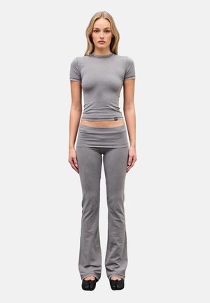 Woman standing facing forward wearing a fitted grey short-sleeve crop top, matching grey flare pants, and black split-toe shoes.