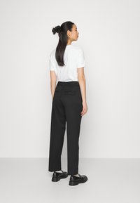 Top branco de manga curta, calças pretas de cintura alta com um bolso atrás e sapatos pretos com uma sola espessa. Tecido suave, ajuste adequado.
