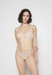 Naakte kanten beha en bijpassende string, met bloemenborduursels, zachte mesh en geschulpte randen, voorzien van verstelbare bandjes en een sluiting aan de voorkant.