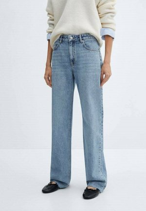 Jasnoniebieskie jeansy z wysokim stanem i prostymi nogawkami w połączeniu z czarnymi balerinami oraz kremowym swetrem z niebieskimi mankietami widocznymi.