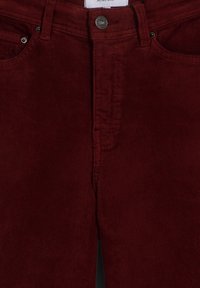 Pantalones de sarga burdeos con cierre de botón, diseño de cinco bolsillos y textura de canalé vertical. Etiqueta con el nombre de la marca visible en la parte superior.
