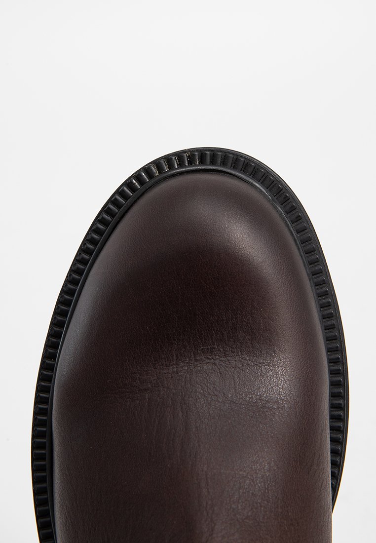 Braune Leder-Schuhe mit glatter Oberfläche, runder Zehenpartie und einer kontrastierenden schwarzen Gummisohle mit strukturiertem Rand.