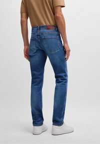 Blauwe denim jeans met een slim fit, voorzien van een leren logo patch op de tailleband, subtiele vervaging en twee achterzakken.