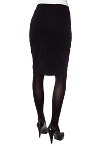 Musta kynähame, joka on valmistettu joustavasta kankaasta, yhdistettynä mustiin tiukkoihin sukkahousuihin ja mustiin korkokenkiin. Suunnittelu on tiukasti istuva ja polvipituinen.