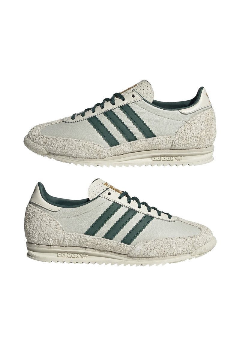 Baskets Adidas avec une tige en cuir blanc et des accents verts, suède crème texturé au niveau des orteils et du talon, et une silhouette rétro.