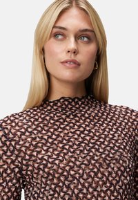 Top à manches longues en tissu noir transparent avec un motif incurvé, présentant un col haut et des bords festonnés, conçu pour une coupe ajustée.