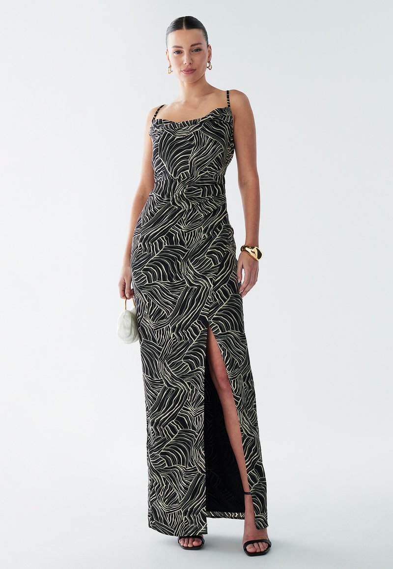 Maxi dress in black with a wavy white pattern. Features thin straps, form-fitting design, and a thigh-high slit. Smooth texture.