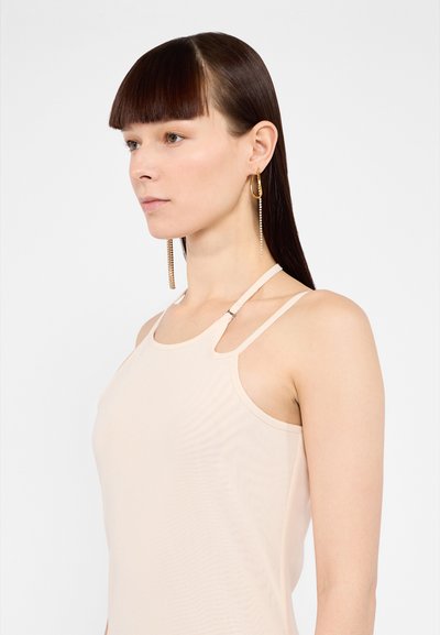 Light beige sleeveless top with thin straps, featuring a subtle sheen and a slight fitted design. Notable hardware detail at the neckline.