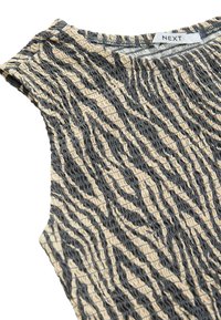 Top ajusté sans manches avec un motif zèbre beige et noir. La texture est froncée, créant un effet ondulé. Étiquette de marque visible.