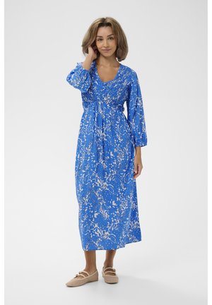 Vestido maxi floral azul con cuello en V, mangas largas abullonadas y cintura elástica. Combinado con zapatos planos beige tejidos.