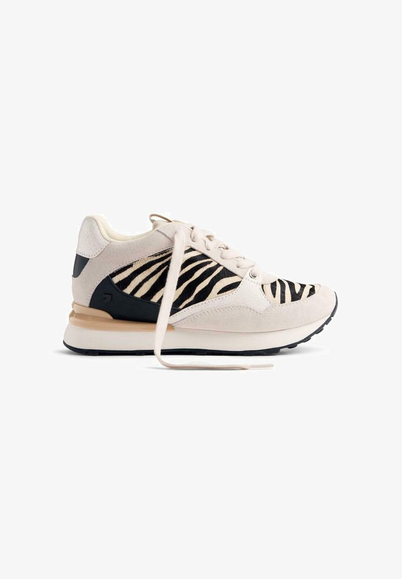 Sneaker con tomaia in suede beige, pannello in tessuto a strisce bianco e nero, dettagli neri e suola marrone chiaro. I lacci sono bianchi e slacciati.