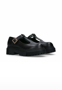 Scarpe T-strap in pelle nera con suola in gomma nera spessa, con un dettaglio decorativo a fibbia sulla cinghia e una punta rotonda.