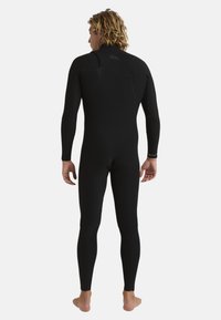 Black wetsuit made from stretchy neoprene; long sleeves and legs; flatlock seams; minimalist design with no prominent logos or patterns.