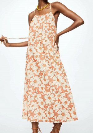 Robe maxi fleurie avec bretelles spaghetti réglables, en couleurs pêche et crème, présentant un motif floral et des poches latérales.