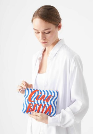 Pochette rayée bleu et blanc avec l'inscription rouge "Ciao Bella", équipée d'une fermeture à glissière et d'une anse pour un transport facile. Matériau en toile lisse.