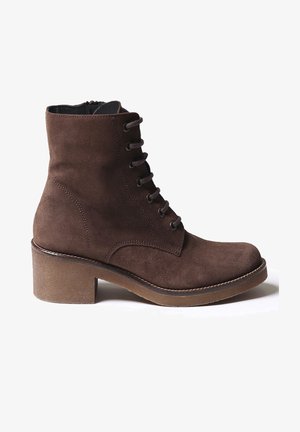 Bottine en daim marron à bout rond, à lacets sur le devant, avec un talon épais. Présente des détails de couture subtils le long des bords.