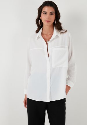 White button-up shirt made of lightweight fabric with a single chest pocket, long sleeves, and classic collar. Smooth texture, relaxed fit.