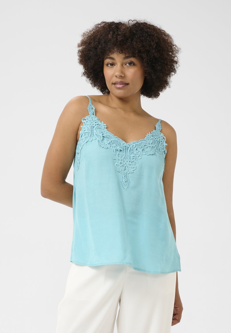 Šviesiai mėlynas camisolė, pagaminta iš lygaus audinio. Pasižymi sudėtingu nėriniu aplink iškirptę ir plonomis reguliuojamomis petnešomis.