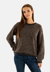 Pull en imprimé léopard dans des tons de marron et de noir, fabriqué en matériau doux avec une coupe ample et un col et des poignets côtelés.