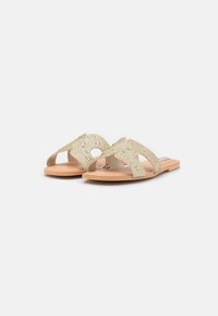 Goldene, offene Riemensandalen mit strukturierten Riemen und dekorativen Akzenten. Flache, beige Sohle, Fußbett mit Konturen für Komfort.