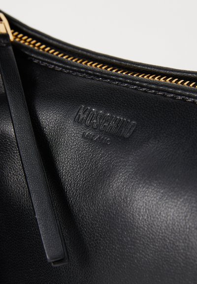 Geantă din piele neagră cu suprafață texturată, închidere cu fermoar aurit și logo-ul embosat "Moschino Milano" pe interior.