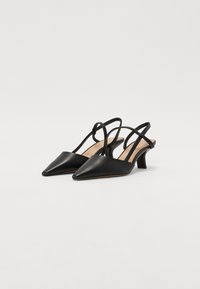 Talons aiguilles slingback en cuir noir avec des bouts pointus, de fines lanières et un petit talon carré. Texture lisse avec des détails minimalistes.