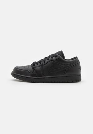 Sort lavtop sneaker med perforeret tå, snørebånd og Nike-logo på siden, vist på hvid baggrund.