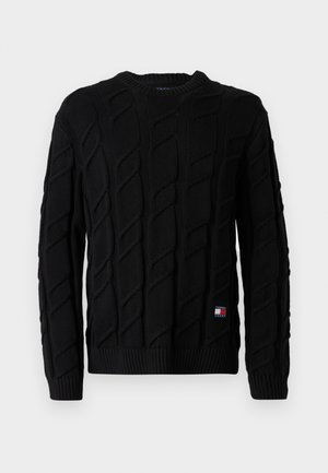 Maglione nero lavorato a maglia con un motivo a trecce testurizzato, polsini e bordo a costine, con una piccola etichetta del logo sul lato sinistro in basso.