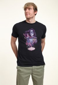 Camiseta negra de manga corta con un gráfico colorido de una superheroína en acción, detallada con colores vibrantes y poses dinámicas.