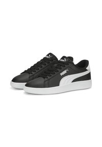 Baskets de sport noires en cuir synthétique avec une semelle en caoutchouc blanche. Présente un logo blanc et un design à rayures contrastées. Forme de bout arrondi.