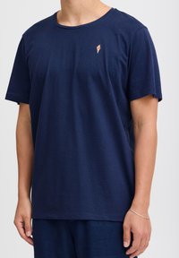 Marine kortærmet t-shirt lavet af bomuld. Har et lille isvaffelgrafik på venstre bryst. Klassisk rund halsudskæring, afslappet pasform.
