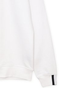 Felpa bianca con un tessuto strutturato, polsini a costine e una striscia nera in evidenza all'orlo della manica. Design semplice e classico.