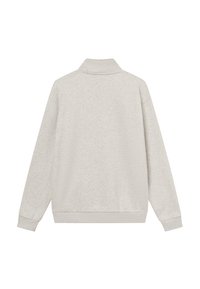 Gaiši pelēks krekls, brīvs piegriezums, mīksta tekstūra, augsts apkakle, garas piedurknes, un ribotas aproces un apakšmala. Vienkāršs, bez redzamas zīmola.