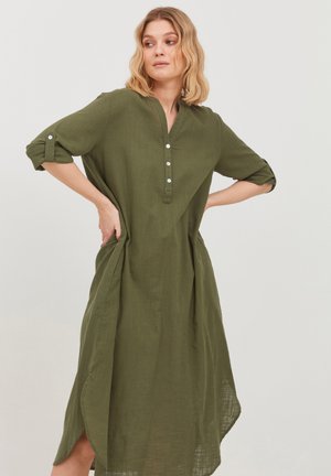 Green linen dress with a collared neckline, three buttons, and three-quarter sleeves. Features side pockets and a curved hemline.