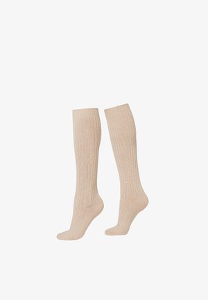 Beige knähöga strumpor med ribbad struktur. Tillverkade av ett mjukt material, med förstärkt tå och en mjuk toppkant för komfort.