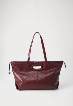 Sac en cuir cramoisi avec une finition texturée, doubles poignées et une ouverture frontale bien en vue. Doté d'un charme décoratif en argent sur le côté.