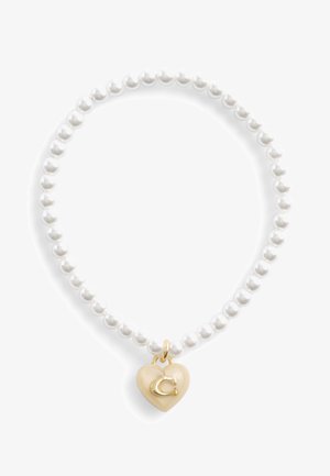 Bracciale di perle con un ciondolo a forma di cuore dorato. Il ciondolo è di un beige chiaro con la lettera "C" impressa. Perle bianche distribuite uniformemente formano il bracciale.